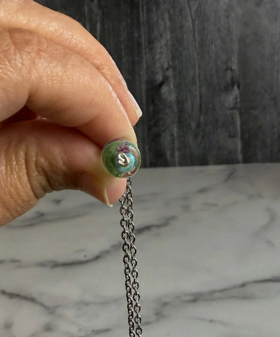 Close-up of a hand holding the bottom of a necklace with a wired knot