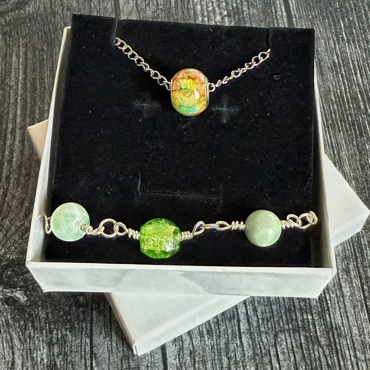 Necklace with green and yellow beads in a box on a wooden surface