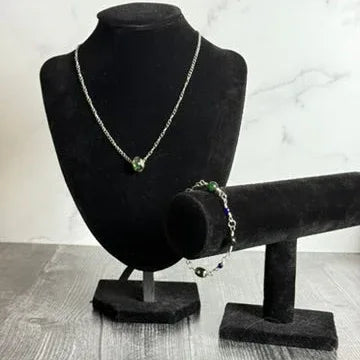 Necklace and bracelet on black velvet stands against a marble background
