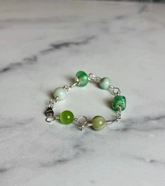 Green beaded bracelet on a marble surface