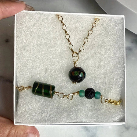 A jewelry set with green and black beads and gold accents