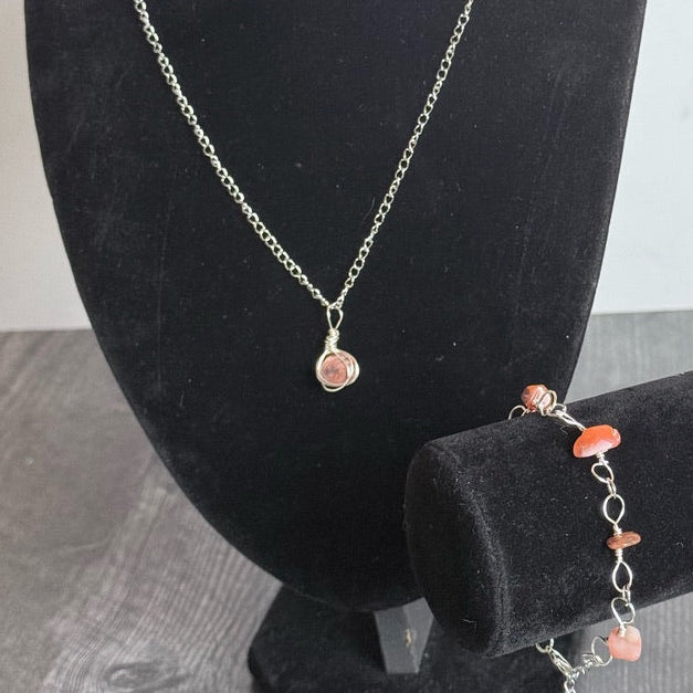 Necklace and bracelet set on black mannequin busts with a neutral background