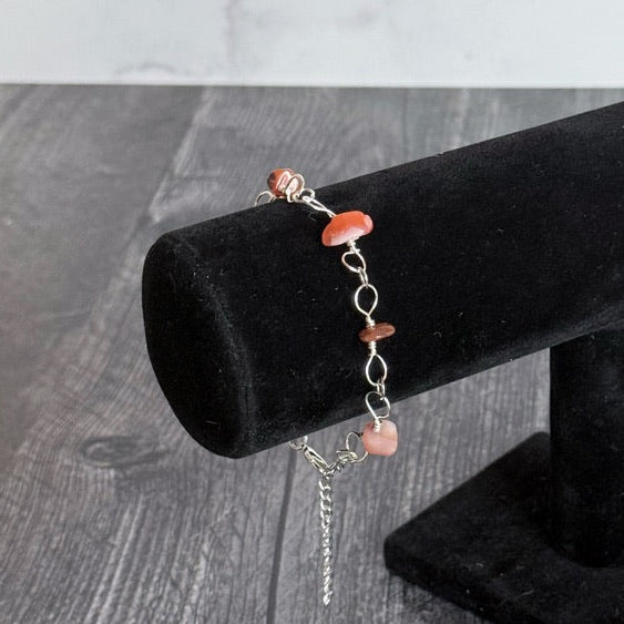Bracelet with coral beads on a black velvet stand against a gray background