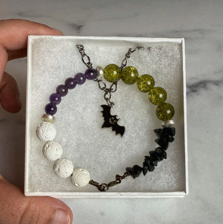 A green, white and purple beaded necklace with a bat necklace