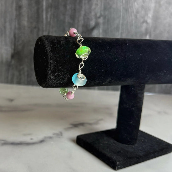 Bracelet with colorful beads on a black velvet stand against a marble background