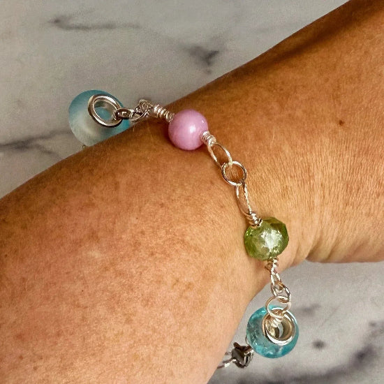 Bracelet with colorful beads on a wrist against a marble background