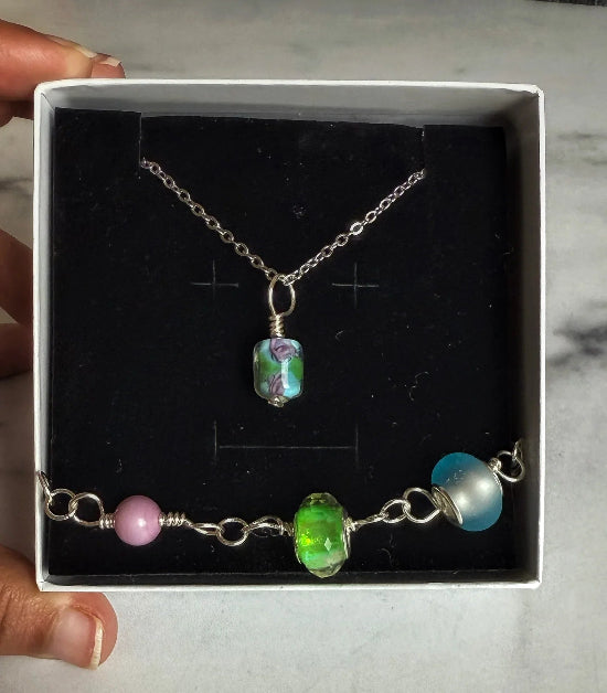 Necklace and bracelet with colorful beads in a box held by a hand