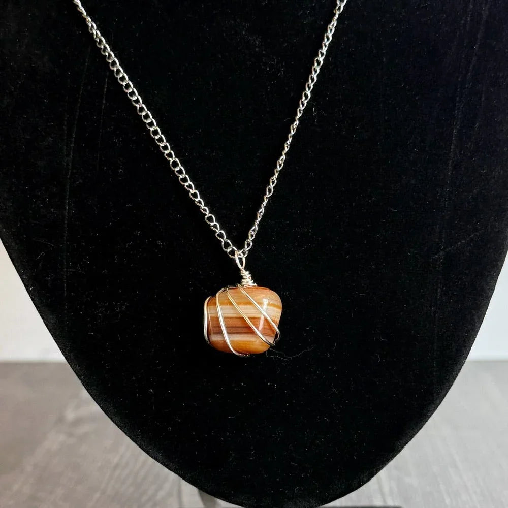 one-of-a-kind Necklace with a carnelian Agate pendant on a black velvet bust against a marble background