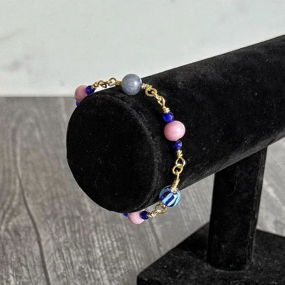 handmade bracelet with colorful glass beads, agate beads and lapis lazul beads on a black velvet stand against a gray background