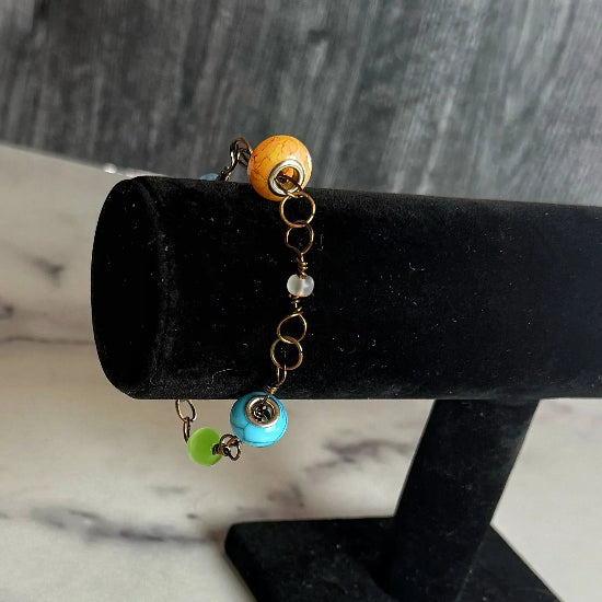 Bracelet with colorful beads on a black stand against a marble background