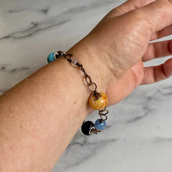 Bracelet with colorful beads on a wrist against a marble background