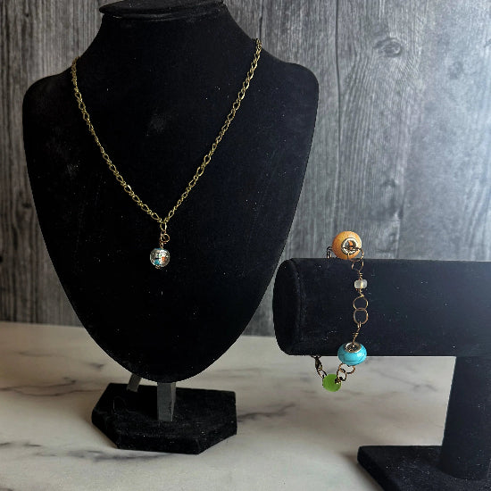 Jewelry set on black mannequin busts against a wooden background