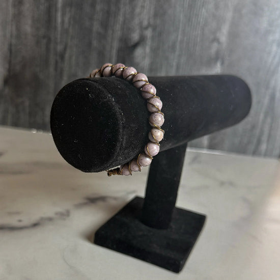 Beaded bracelet on a black velvet stand against a gray wooden background
