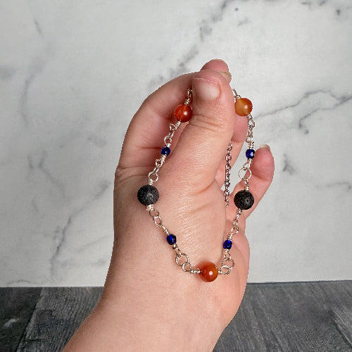 Hand holding a beaded necklace with a marble background