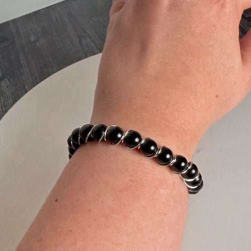 Black beaded bracelet on a wrist with a neutral background