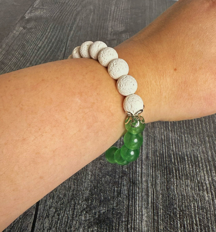 Bracelet with white and green beads on a wrist against a gray background