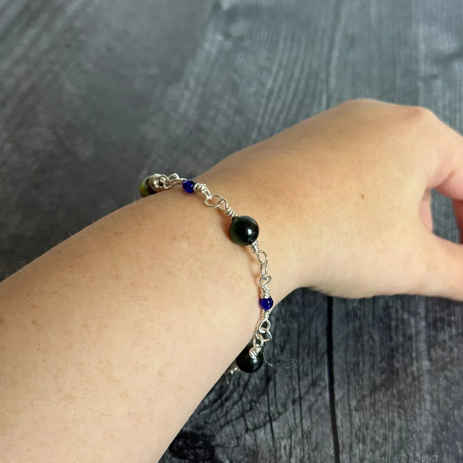 Bracelet with blue and blue beads on a wrist against a wooden background