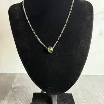Necklace with a green pendant on a black mannequin bust against a white background
