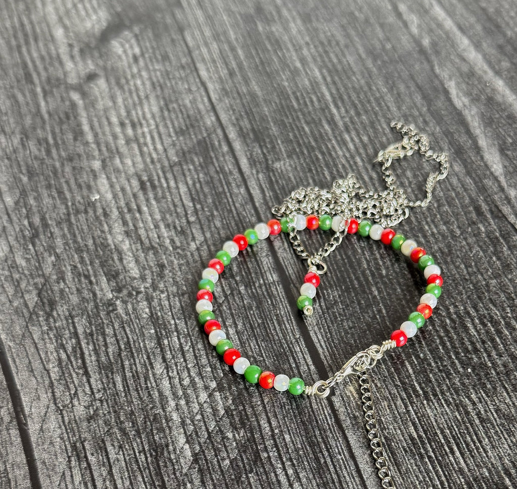 Beaded bracelet with red, green, and clear beads on a wooden surface