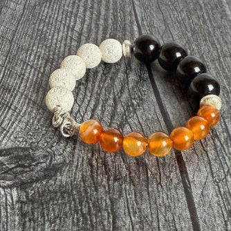 Beaded bracelet with orange, black, and silver beads on a wooden surface