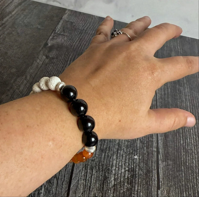 Hand wearing a beaded bracelet on a wooden surface