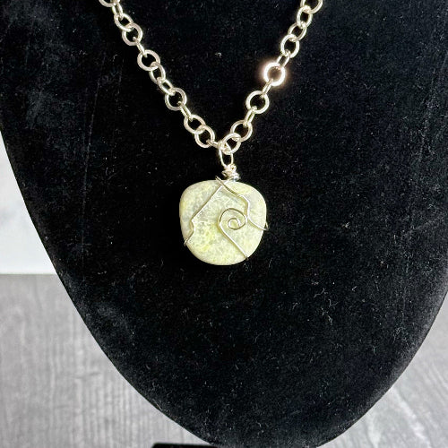 Necklace with a round pendant on a black velvet stand