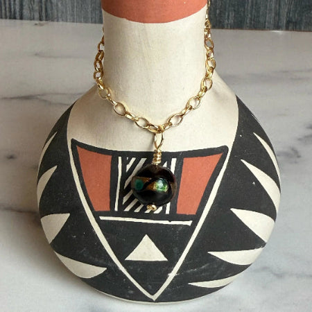 black necklace with gold chain on a decorative bust
