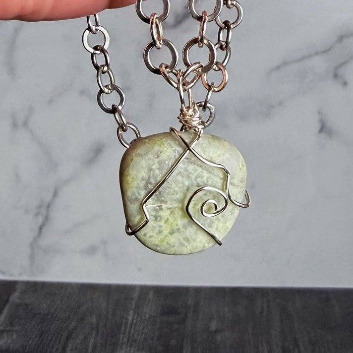 Necklace with a green stone pendant on a marble background