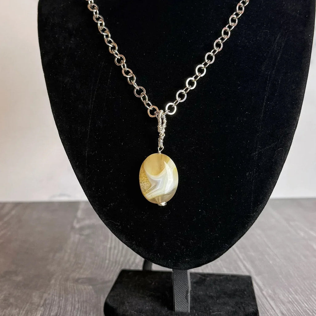 Necklace with a citrine pendant on a black bust against a neutral background