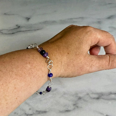 Hand wearing a beaded bracelet on a marble surface