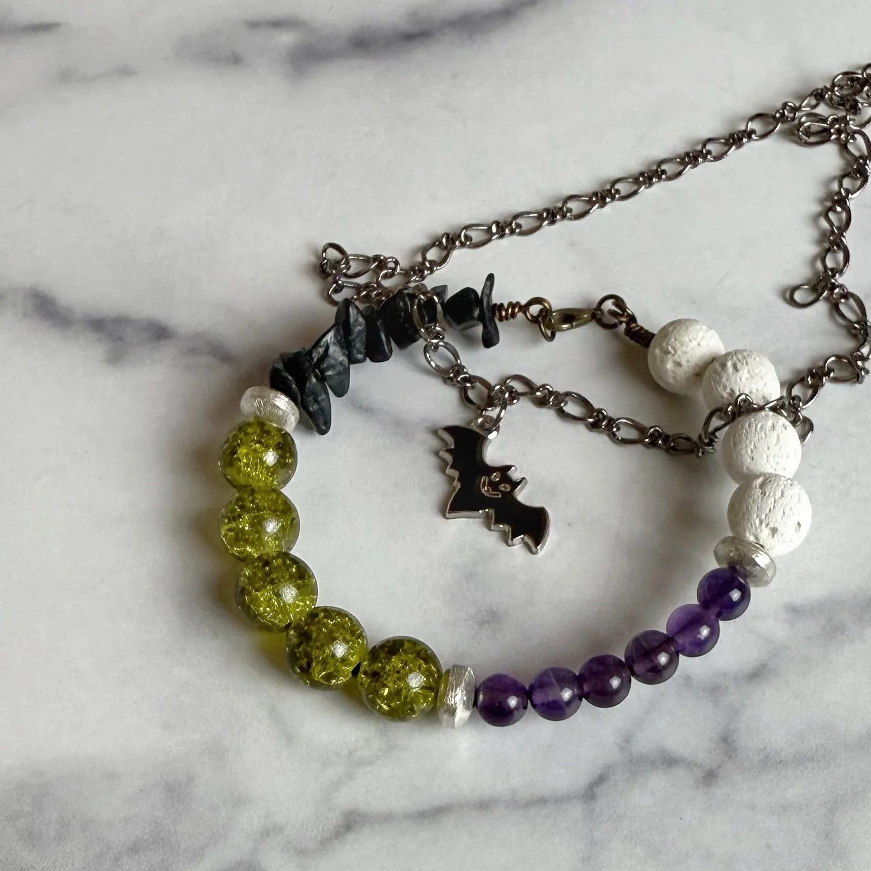 beaded Bracelet with beads and necklace with batcharms on a marble surface