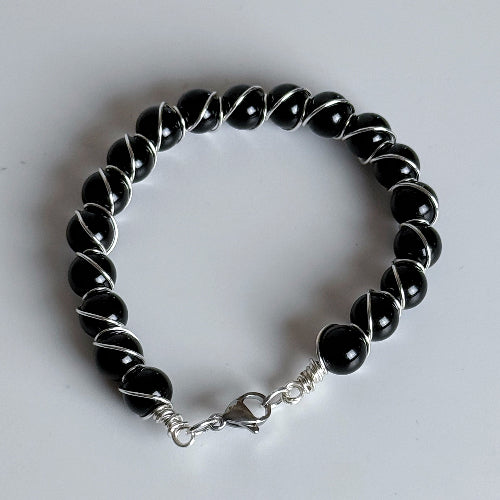 Black beaded bracelet with silver clasp on a white background