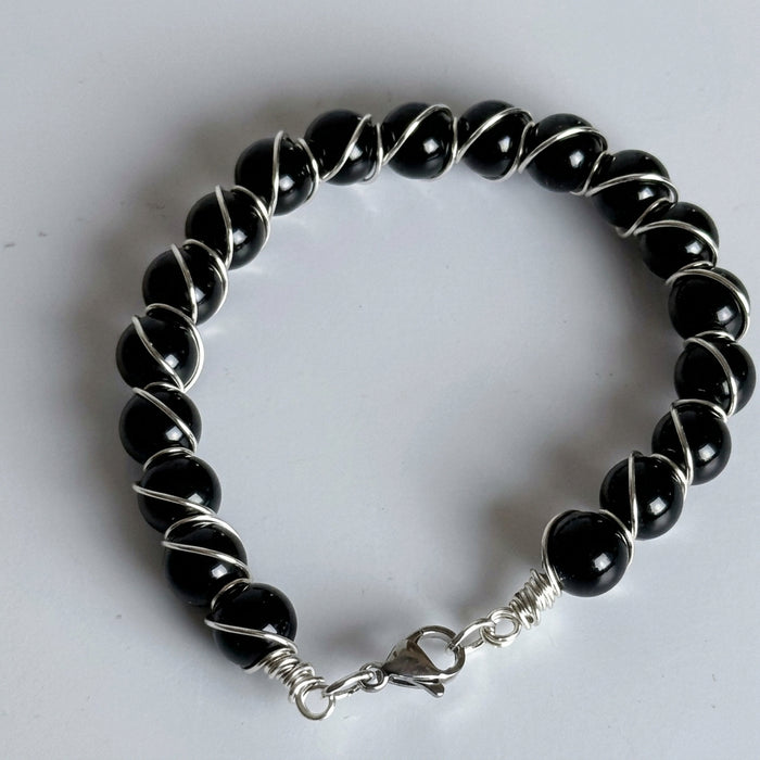 Black beaded bracelet with silver clasp on a white background