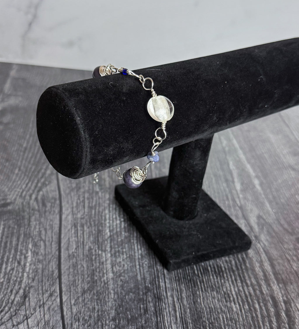 Bracelet with beads on a black velvet stand against a wooden surface