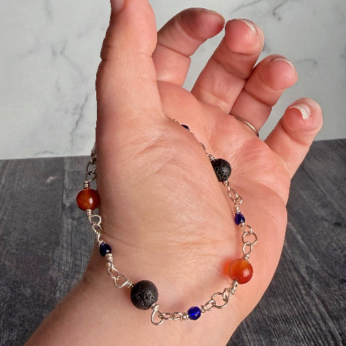 Hand wearing a bracelet with colorful beads on a neutral background