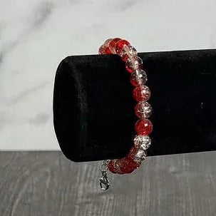 Red beaded bracelet on a black stand against a marble background