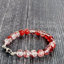 Beaded bracelet with red and clear beads on a wooden surface