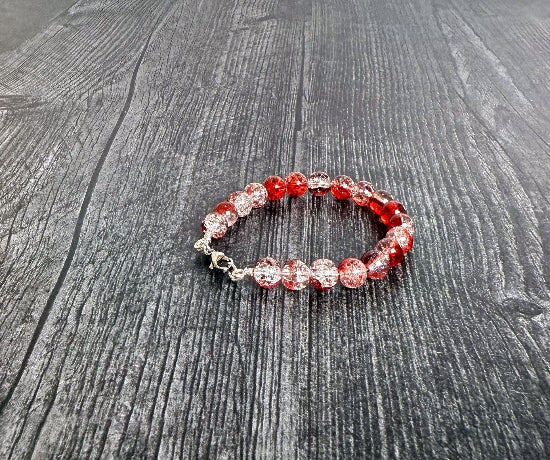 Beaded bracelet with red and clear beads on a wooden surface