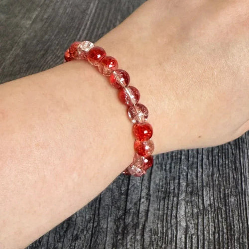 Red beaded bracelet on a wrist against a gray background