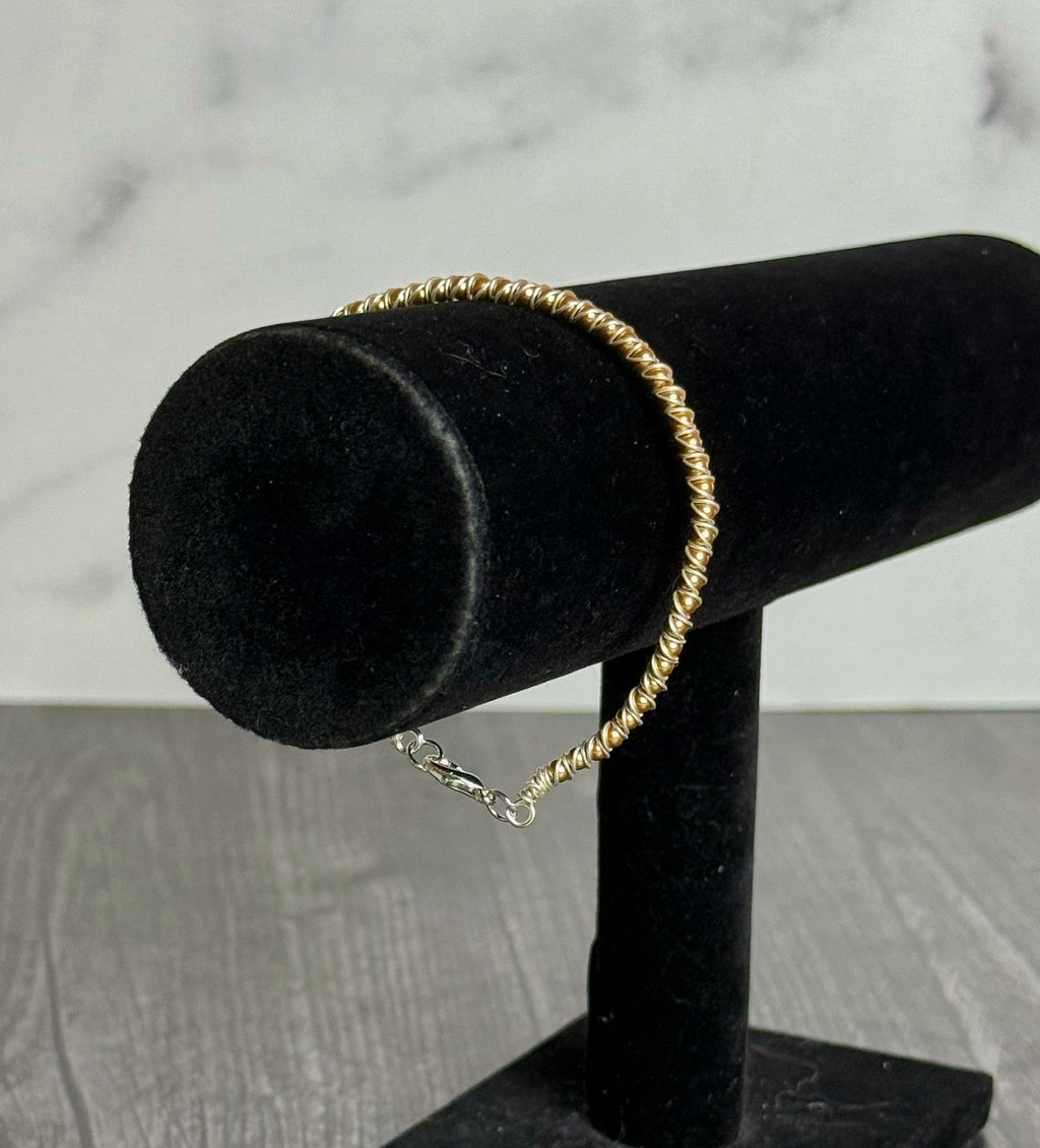 Gold bracelet on a black jewelry stand with a neutral background