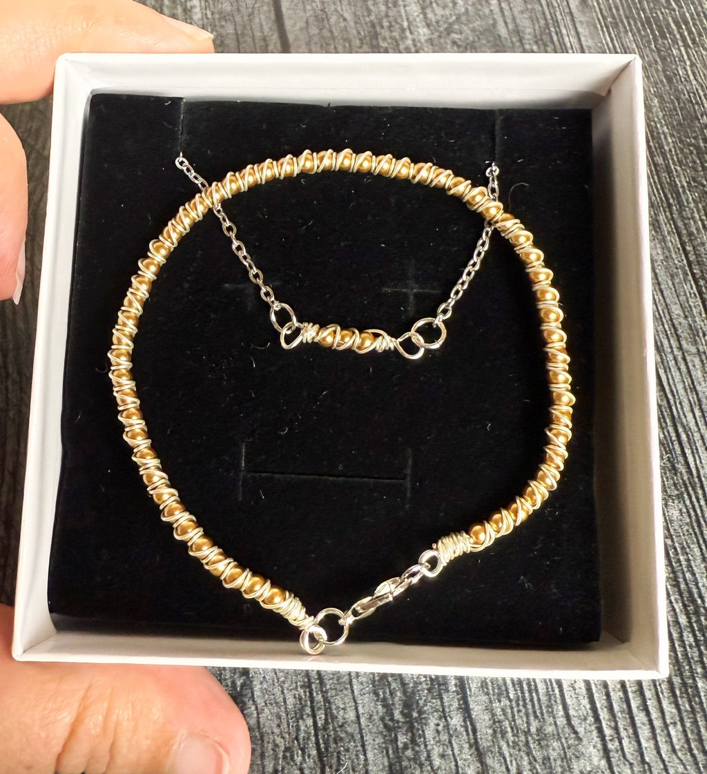 Gold beaded bracelet in a white box on a wooden surface