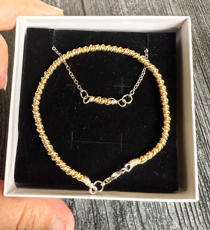 Gold beaded bracelet in a white box on a wooden surface
