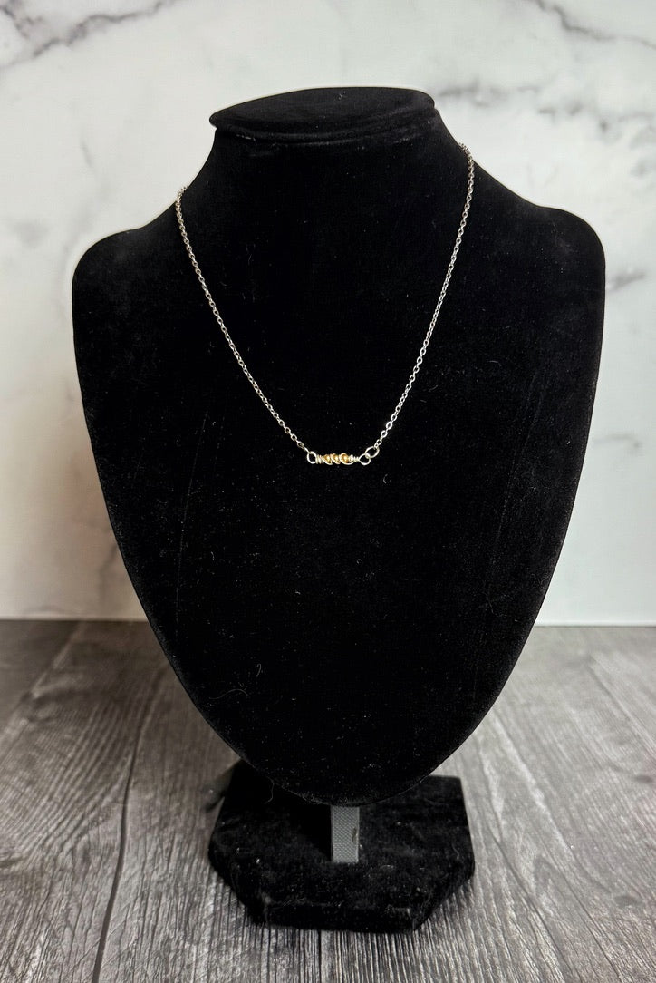 Silver necklace on a black velvet bust against a marble background