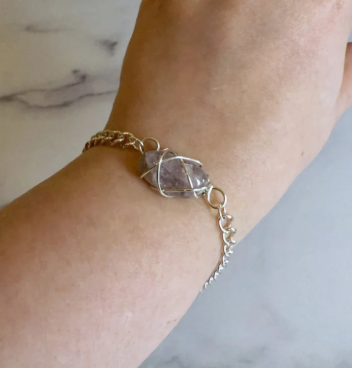 Bracelet with a stone on a wrist against a marble background