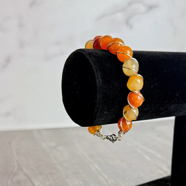 carnelian Beaded bracelet on a black cylindrical stand against a marble background