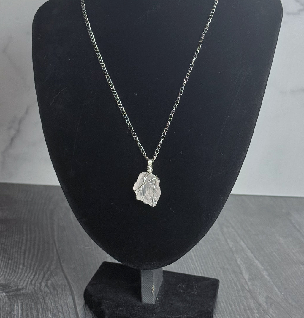 Silver necklace with a pendant on a black mannequin bust against a gray background