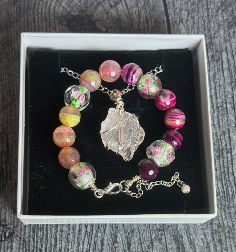 Bracelet with colorful beads and a leaf charm in a box on a wooden surface