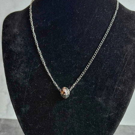 Necklace with a round beaded pendant on a black mannequin bust