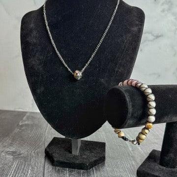 Necklace and bracelet on black velvet stands against a gray marble background